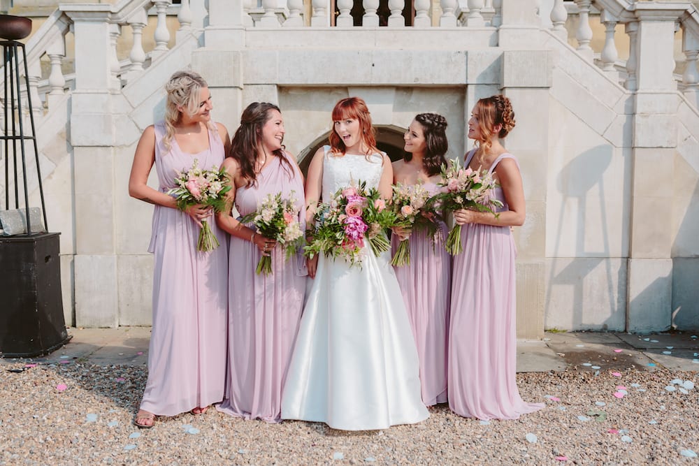 Bridal party with brightly coloured floral bouquets pastel pinks blush