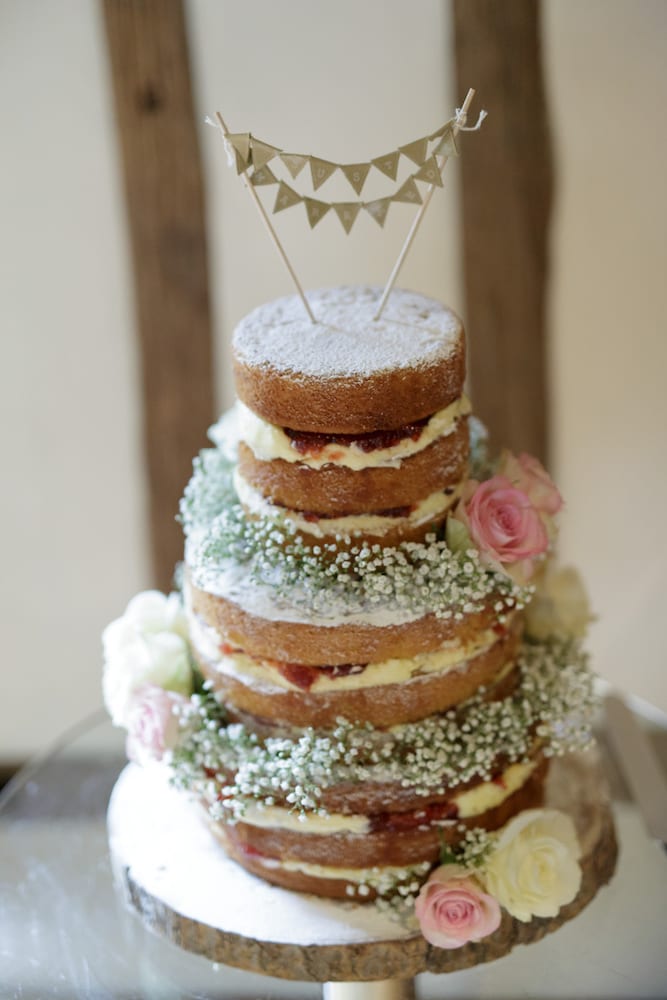 naked sponge wedding cake with pink cream rose gypsophila bunting cake topper