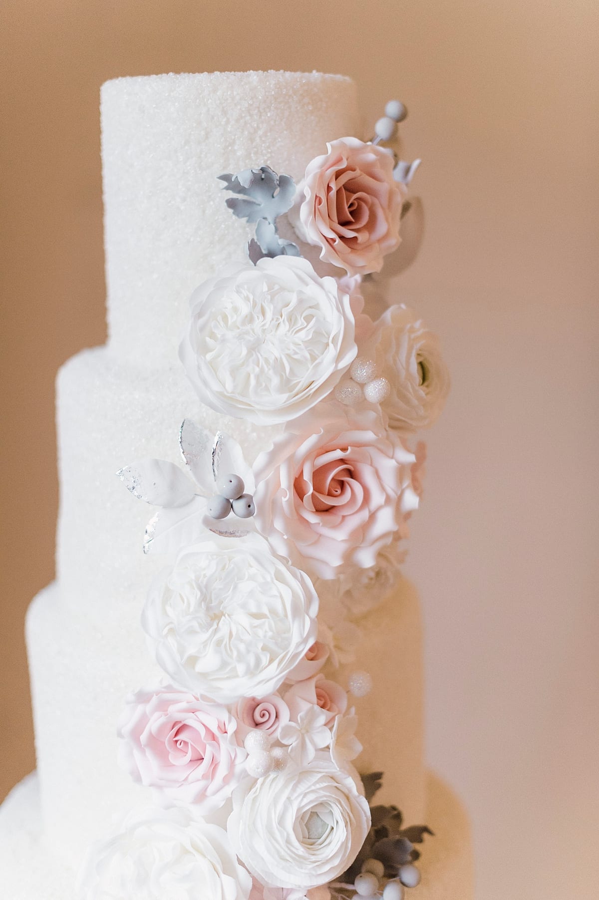 four tier winter wedding cake with edible white snow and spray of flowers cascaded